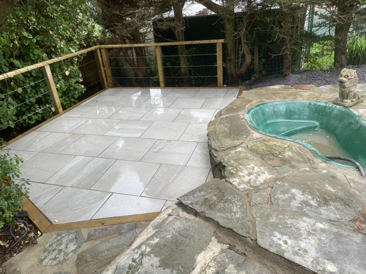 Porcelain patio beside a rock pool feature