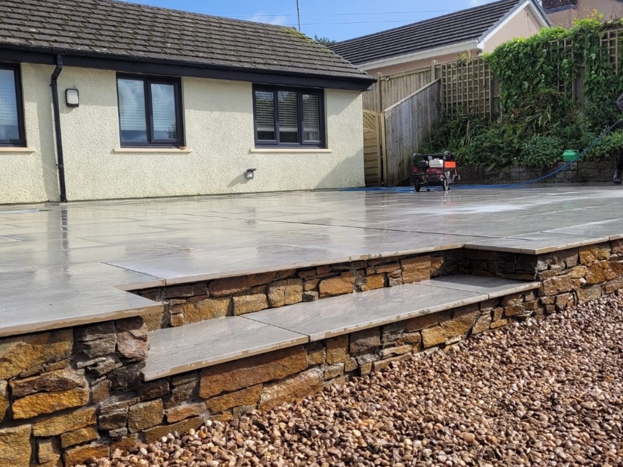 Sandstone patio on a rustic stone retaining wall